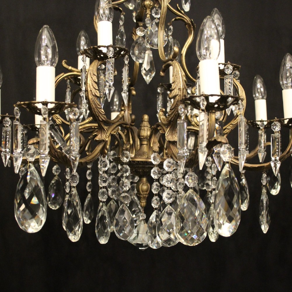 A pair of tiered French brass chandeliers featuring twelve lights each and clear glass crystal drops. View V