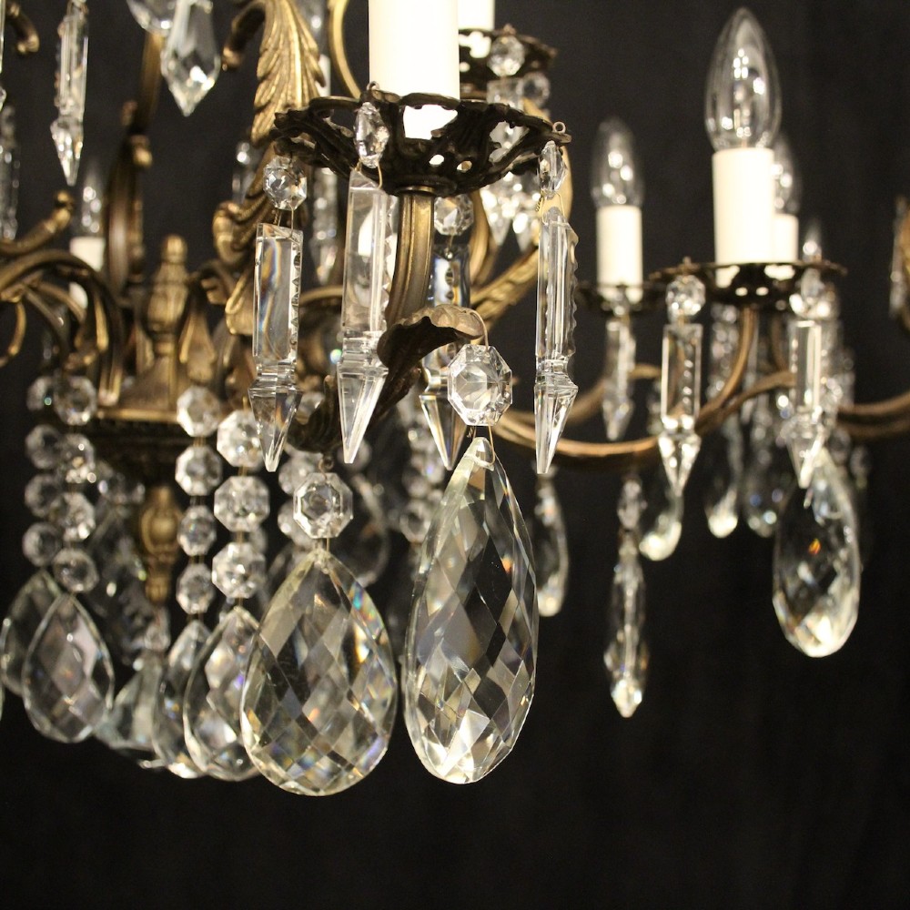 A pair of tiered French brass chandeliers featuring twelve lights each and clear glass crystal drops. View VI