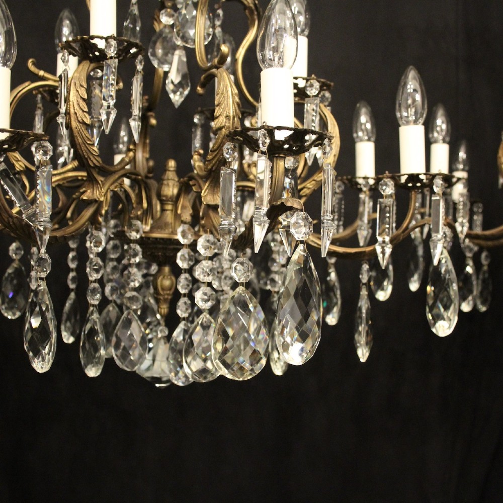 A pair of tiered French brass chandeliers featuring twelve lights each and clear glass crystal drops. View VII