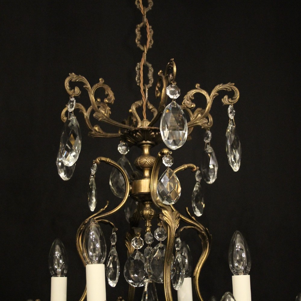 A pair of tiered French brass chandeliers featuring twelve lights each and clear glass crystal drops. View VIII