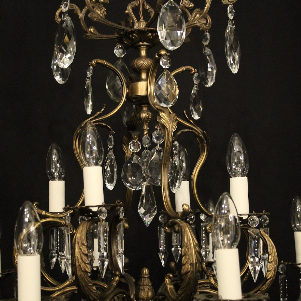 A pair of tiered French brass chandeliers featuring twelve lights each and clear glass crystal drops. View IX