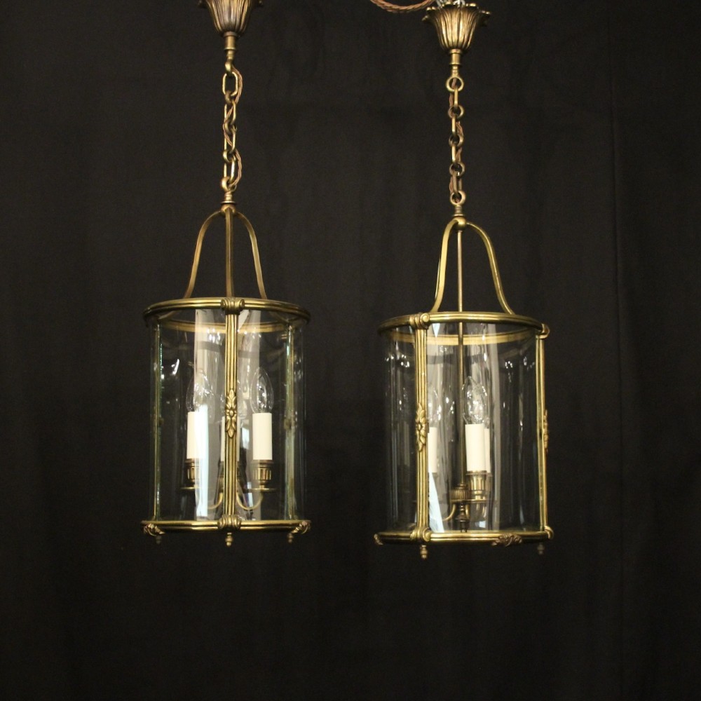 A pair of cylindrical French gilt bronze hanging hall lanterns featuring curved glass panels and internal candle-style light fittings. View II