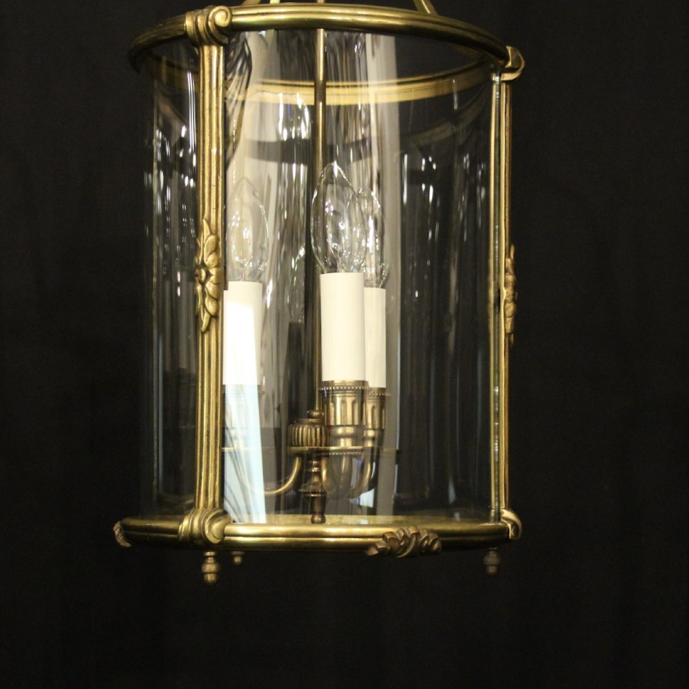 A pair of cylindrical French gilt bronze hanging hall lanterns featuring curved glass panels and internal candle-style light fittings. View IV