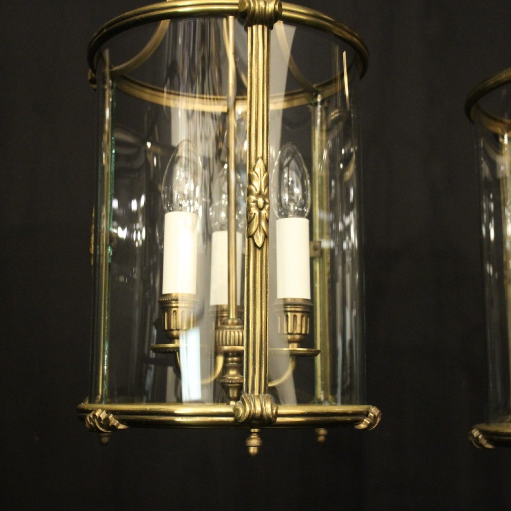 A pair of cylindrical French gilt bronze hanging hall lanterns featuring curved glass panels and internal candle-style light fittings. View IX