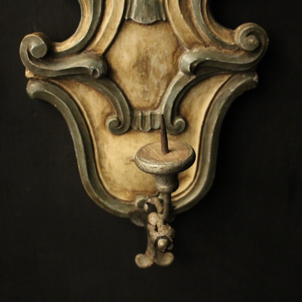 A pair of carved Italian Florentine wall sconces in distressed cream and sage green paint, featuring acanthus crests and single metal candle prickets. View III