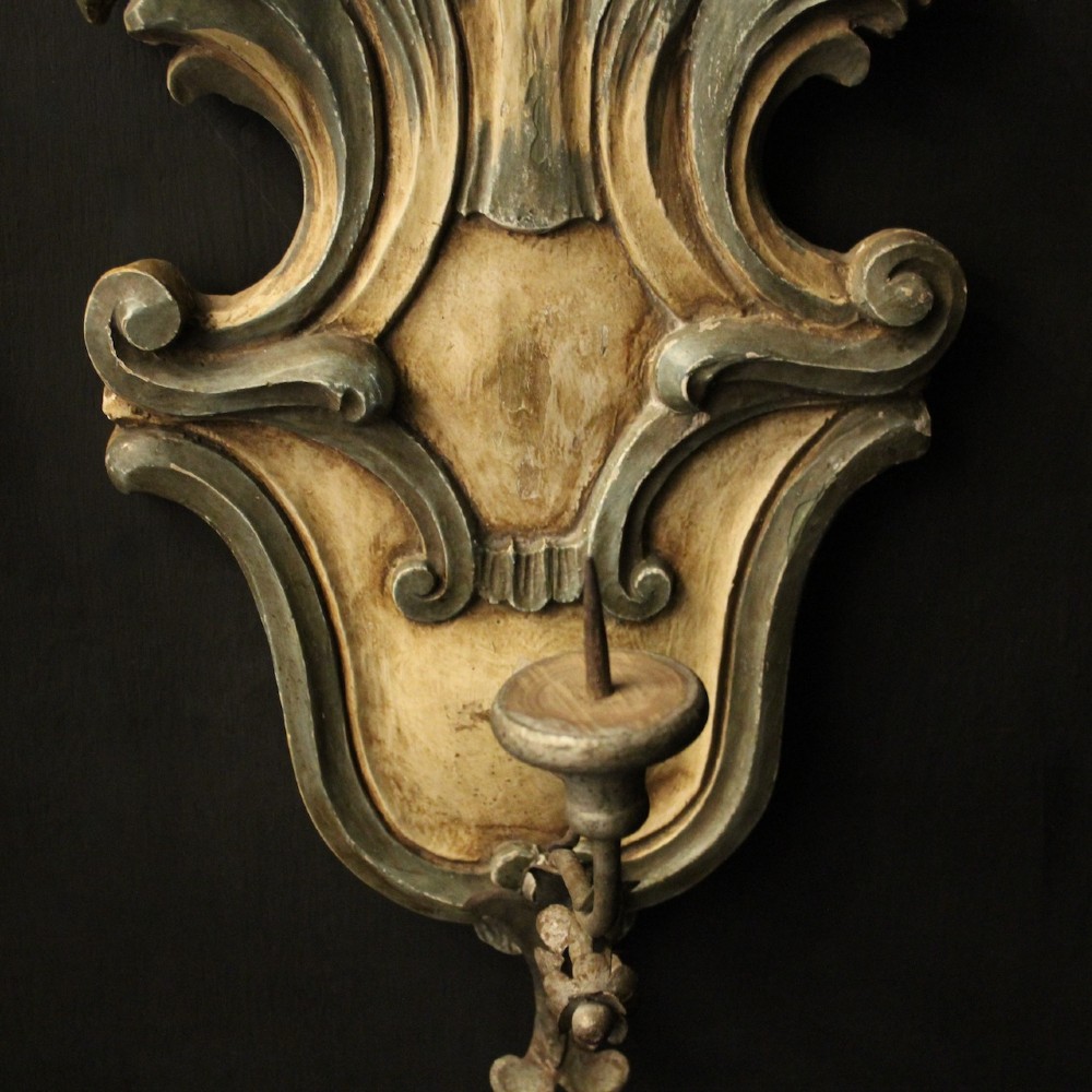 A pair of carved Italian Florentine wall sconces in distressed cream and sage green paint, featuring acanthus crests and single metal candle prickets. View IV