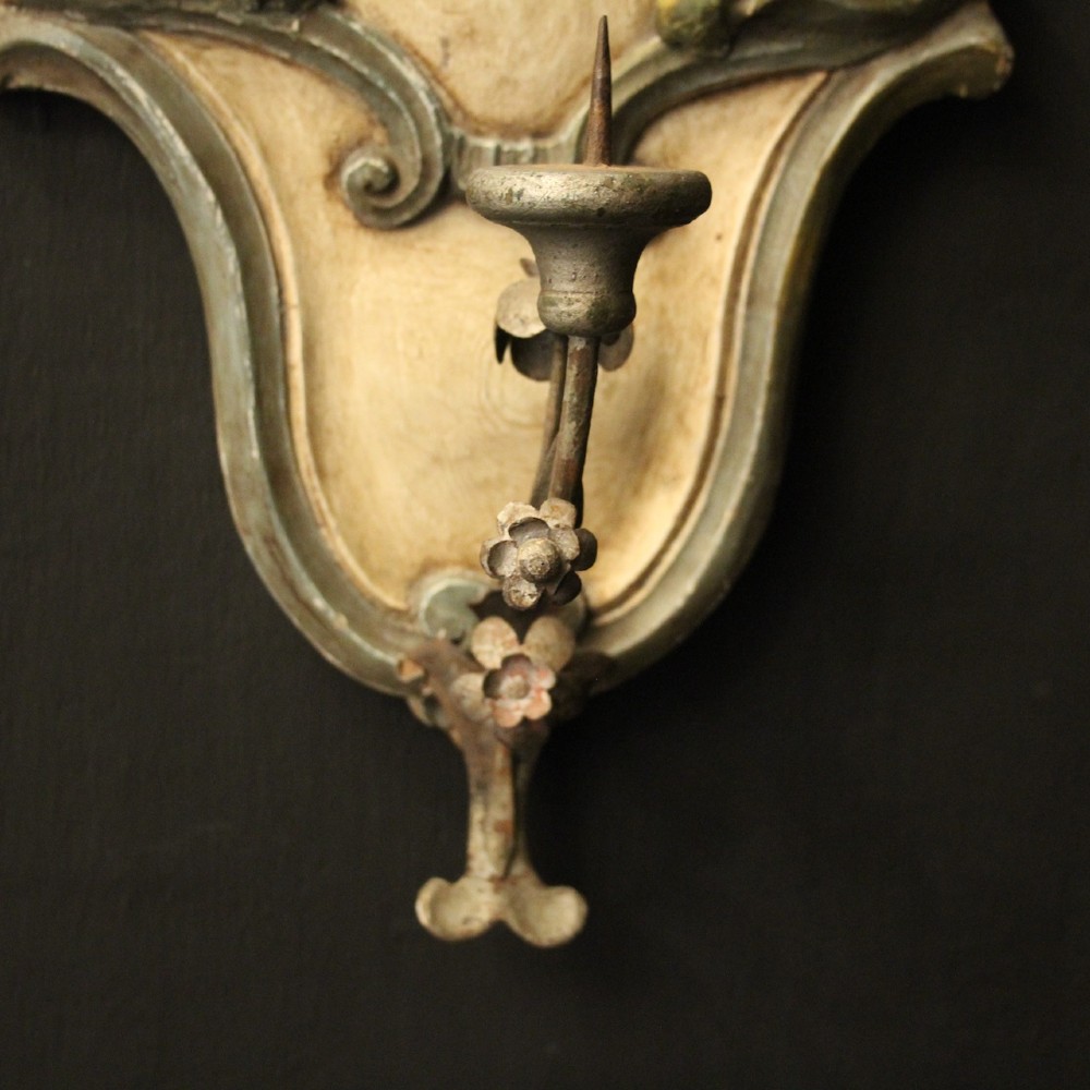 A pair of carved Italian Florentine wall sconces in distressed cream and sage green paint, featuring acanthus crests and single metal candle prickets. View V