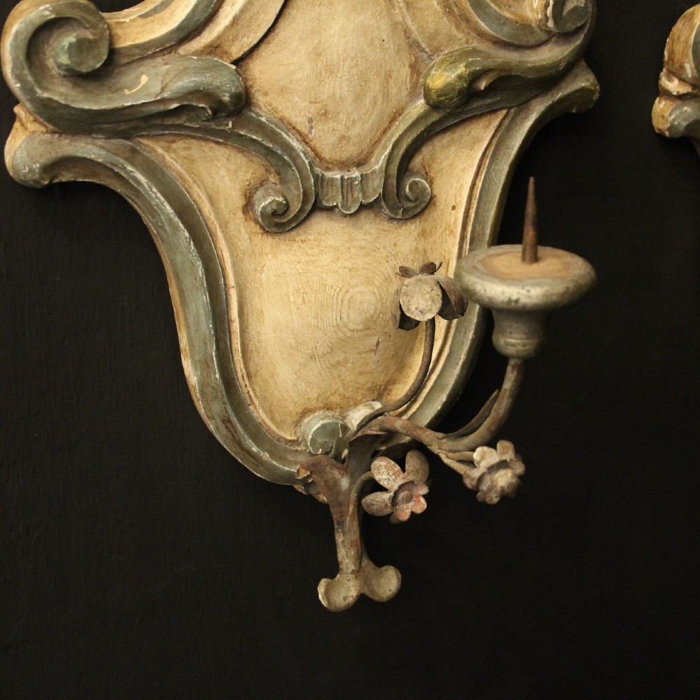 A pair of carved Italian Florentine wall sconces in distressed cream and sage green paint, featuring acanthus crests and single metal candle prickets. View VI