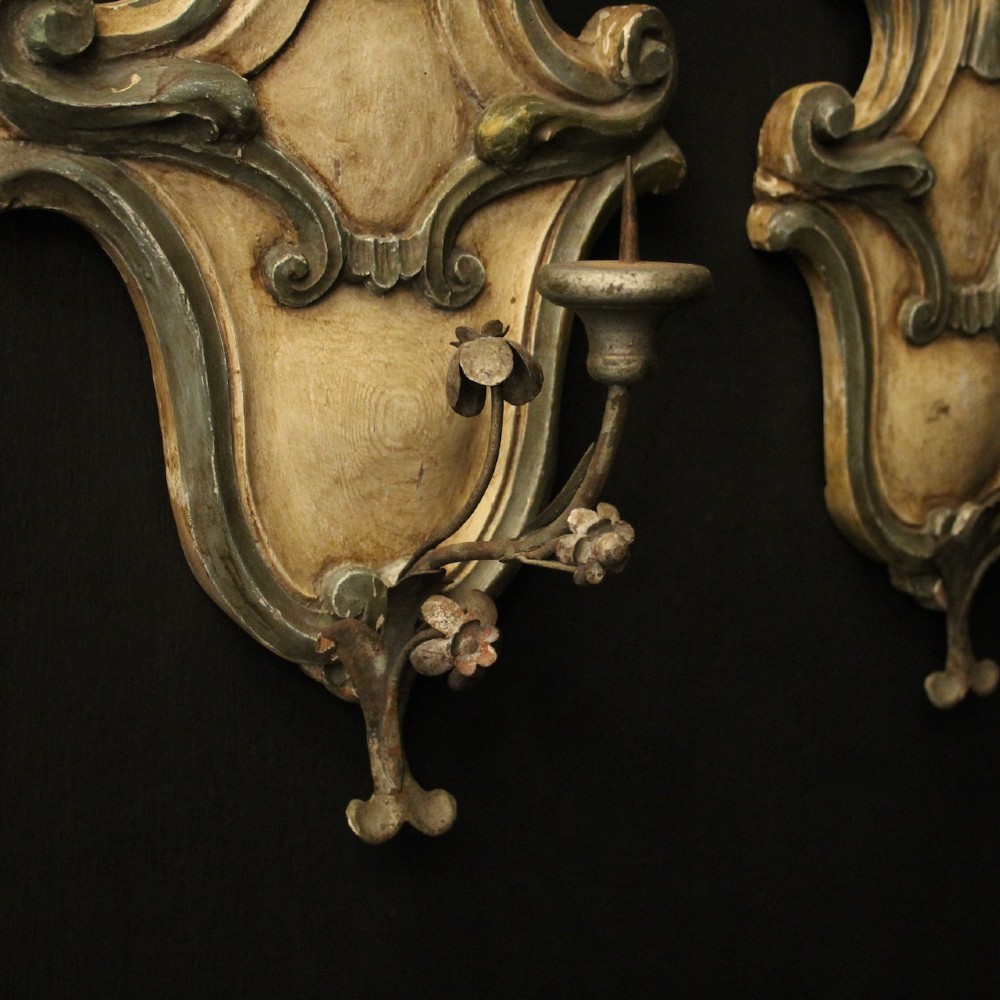 A pair of carved Italian Florentine wall sconces in distressed cream and sage green paint, featuring acanthus crests and single metal candle prickets. View IX