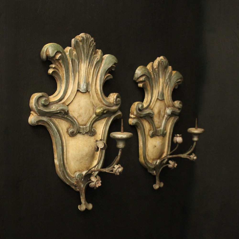 A pair of carved Italian Florentine wall sconces in distressed cream and sage green paint, featuring acanthus crests and single metal candle prickets. View X