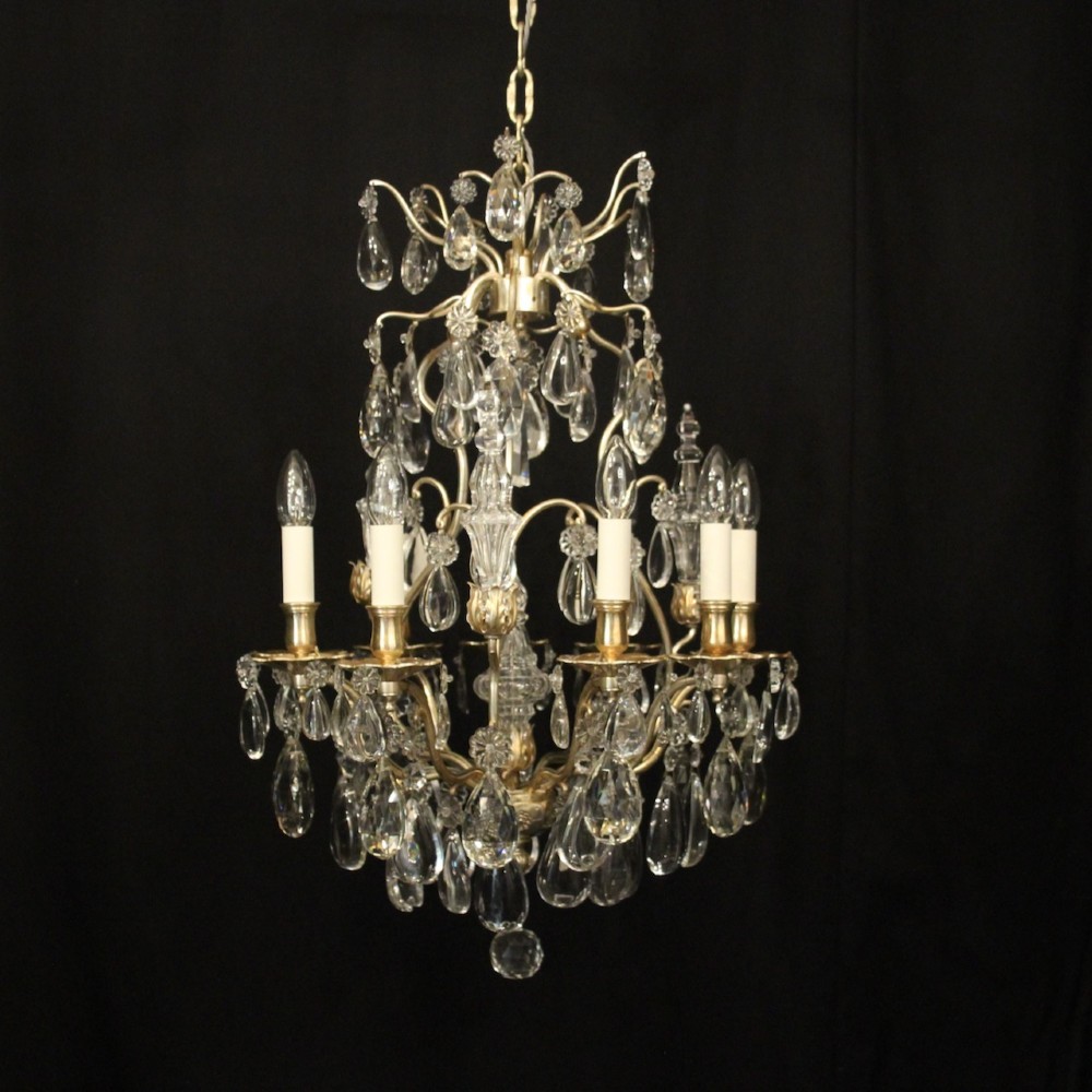 A French nine-light antique chandelier featuring a silver gilded metal frame adorned with cut crystal teardrop pendants and central glass baluster.