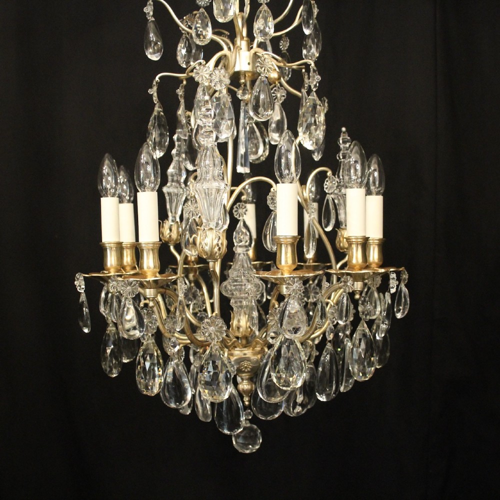 A French nine-light antique chandelier featuring a silver gilded metal frame adorned with cut crystal teardrop pendants and central glass baluster. View II