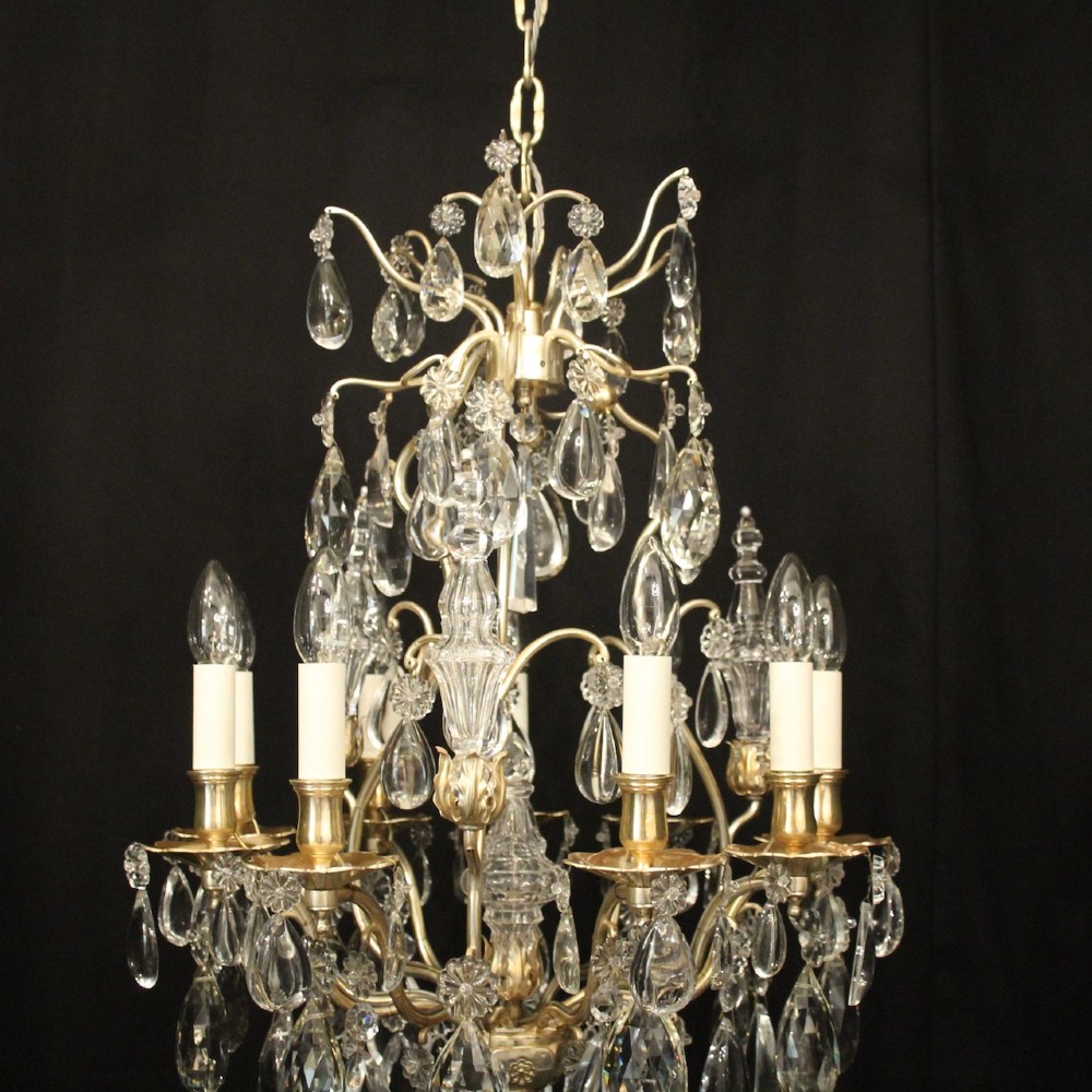 A French nine-light antique chandelier featuring a silver gilded metal frame adorned with cut crystal teardrop pendants and central glass baluster. View III
