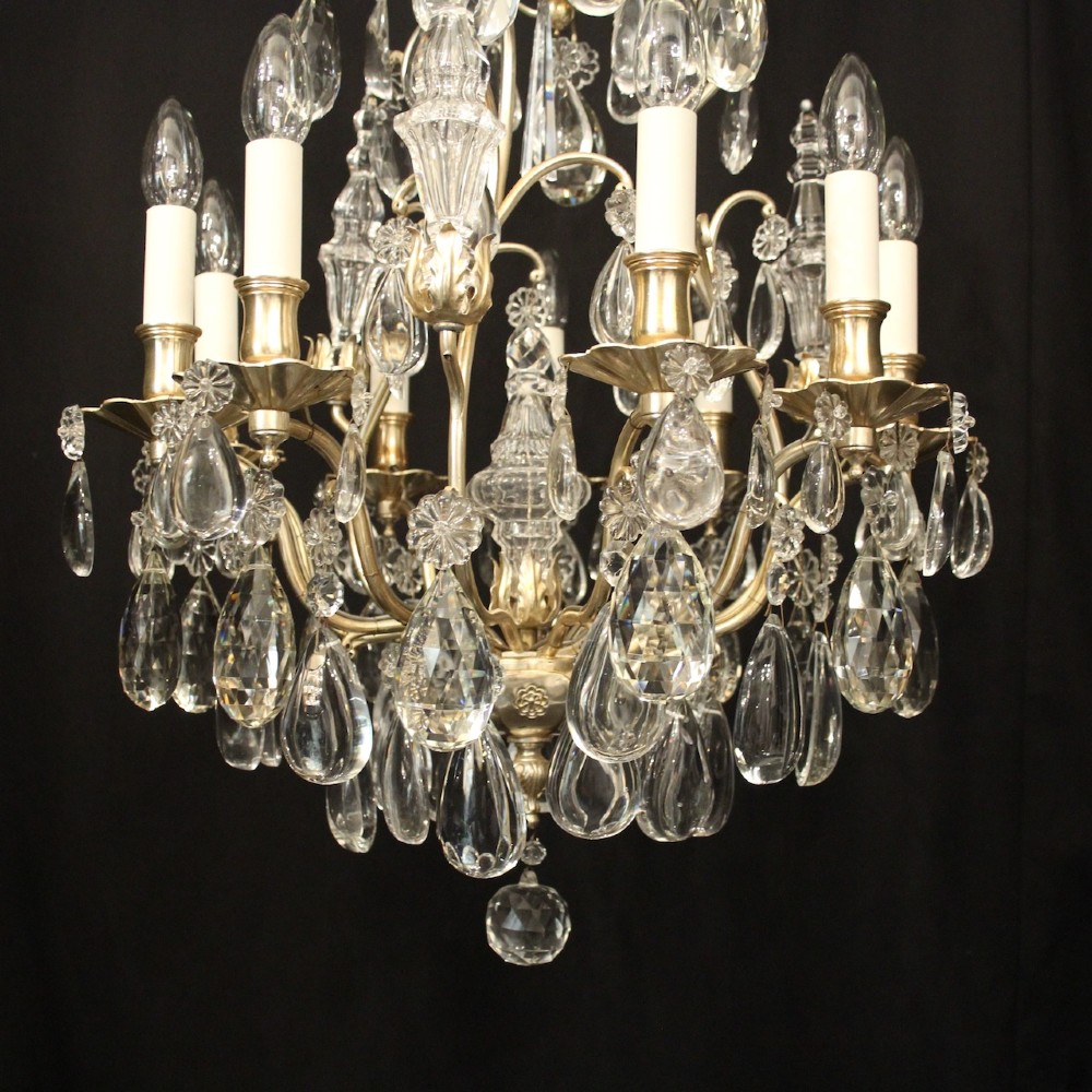 A French nine-light antique chandelier featuring a silver gilded metal frame adorned with cut crystal teardrop pendants and central glass baluster. View IV