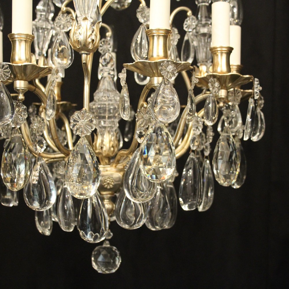 A French nine-light antique chandelier featuring a silver gilded metal frame adorned with cut crystal teardrop pendants and central glass baluster. View V