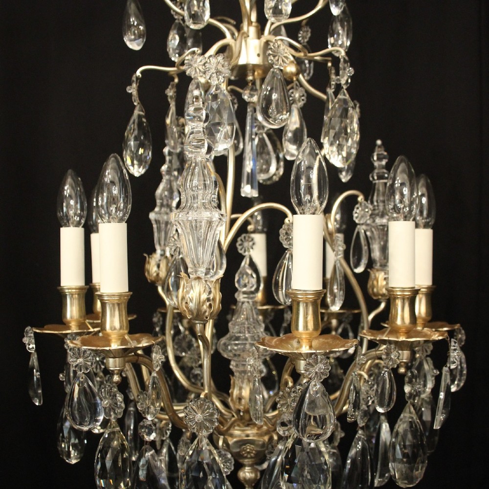 A French nine-light antique chandelier featuring a silver gilded metal frame adorned with cut crystal teardrop pendants and central glass baluster. View VI