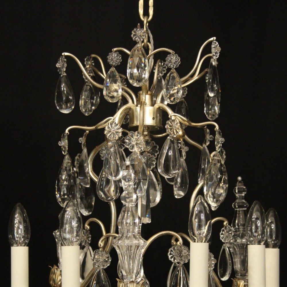 A French nine-light antique chandelier featuring a silver gilded metal frame adorned with cut crystal teardrop pendants and central glass baluster. View IX