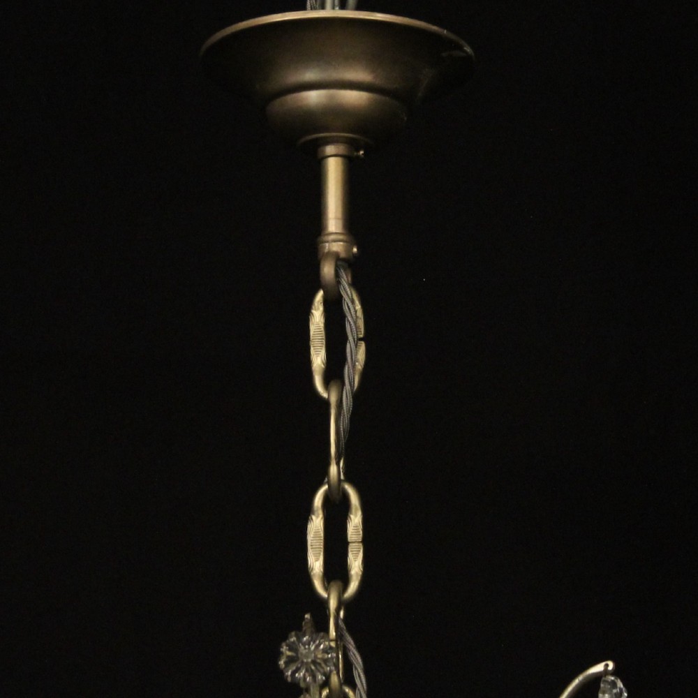 A French nine-light antique chandelier featuring a silver gilded metal frame adorned with cut crystal teardrop pendants and central glass baluster. View X