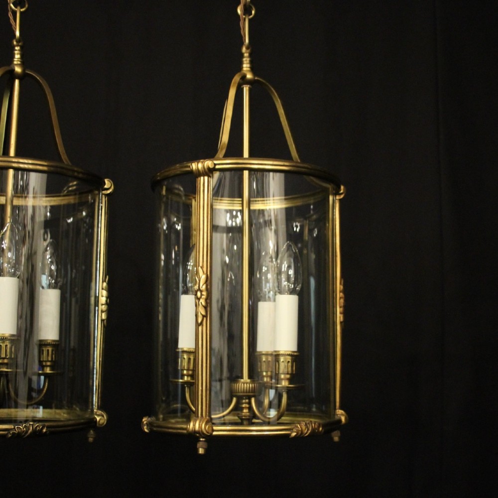 A pair of antique French hall lanterns featuring cylindrical curved glass panels encased in ornate gilded bronze frames with candle-style light fittings. View III