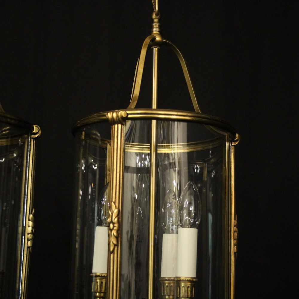 A pair of antique French hall lanterns featuring cylindrical curved glass panels encased in ornate gilded bronze frames with candle-style light fittings. View IV