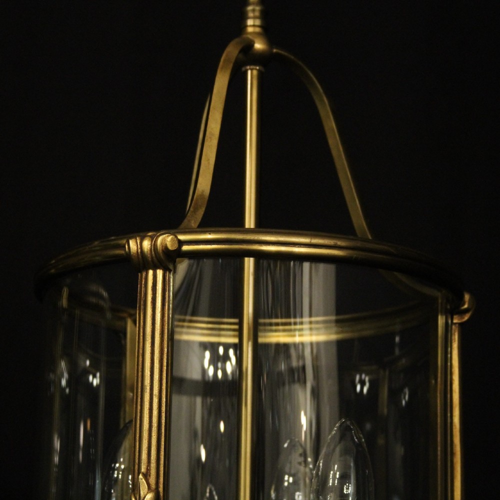A pair of antique French hall lanterns featuring cylindrical curved glass panels encased in ornate gilded bronze frames with candle-style light fittings. View V