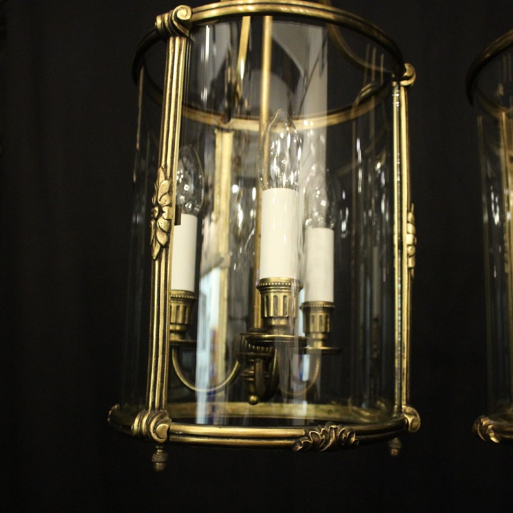 A pair of antique French hall lanterns featuring cylindrical curved glass panels encased in ornate gilded bronze frames with candle-style light fittings. View VI