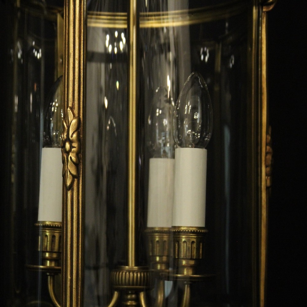 A pair of antique French hall lanterns featuring cylindrical curved glass panels encased in ornate gilded bronze frames with candle-style light fittings. View VIII