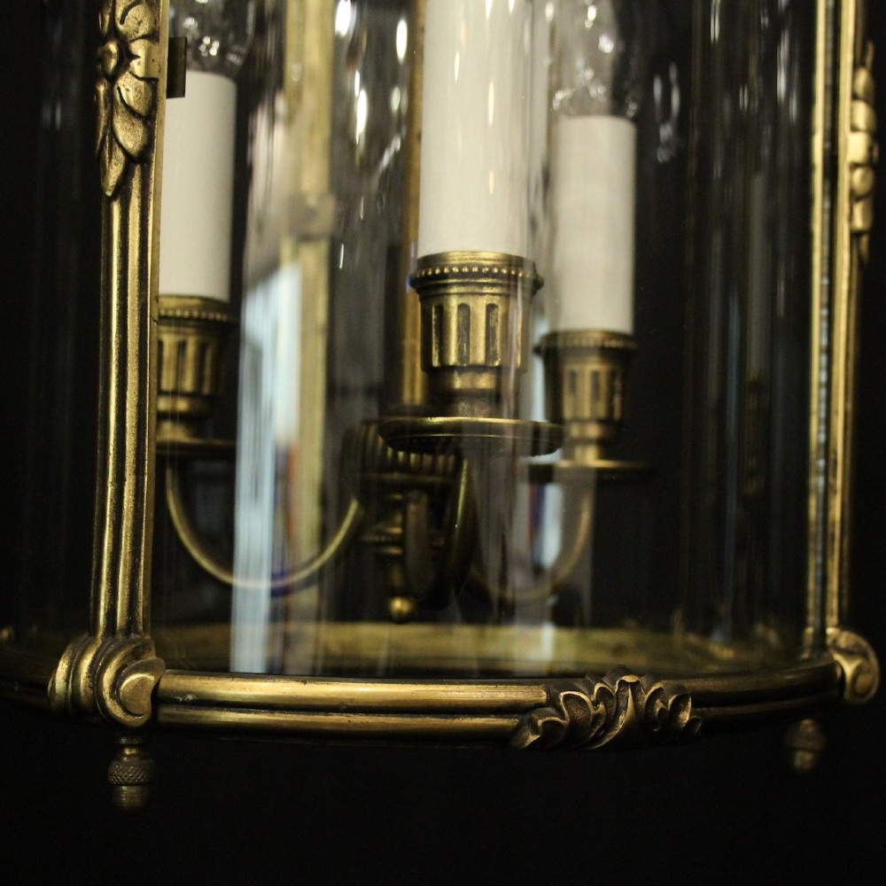 A pair of antique French hall lanterns featuring cylindrical curved glass panels encased in ornate gilded bronze frames with candle-style light fittings. View IX