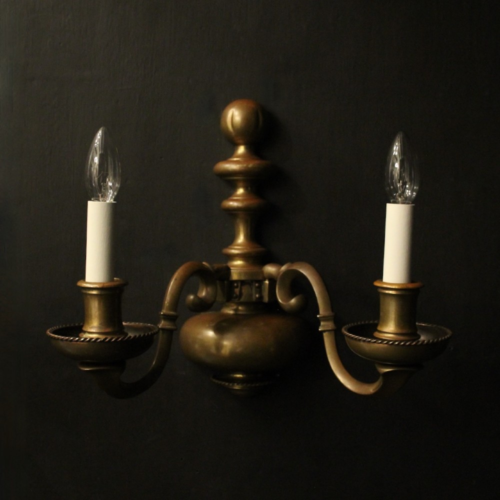 A set of three antique bronze wall sconces, each featuring a turned central baluster and two scrolled arms holding candle-style bulb holders. View II