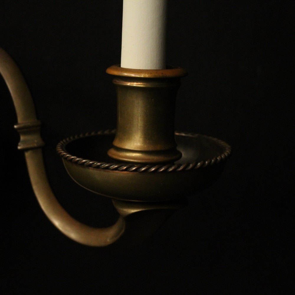 A set of three antique bronze wall sconces, each featuring a turned central baluster and two scrolled arms holding candle-style bulb holders. View IV