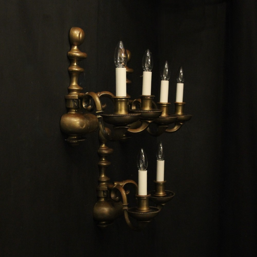 A set of three antique bronze wall sconces, each featuring a turned central baluster and two scrolled arms holding candle-style bulb holders. View IX