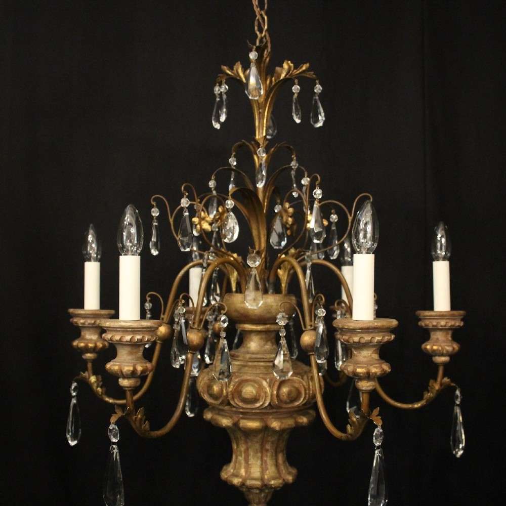 An antique Italian Florentine six-arm chandelier featuring gilded scrolling branches, a carved central column, white candle sleeves, and hanging crystal droplets. View III