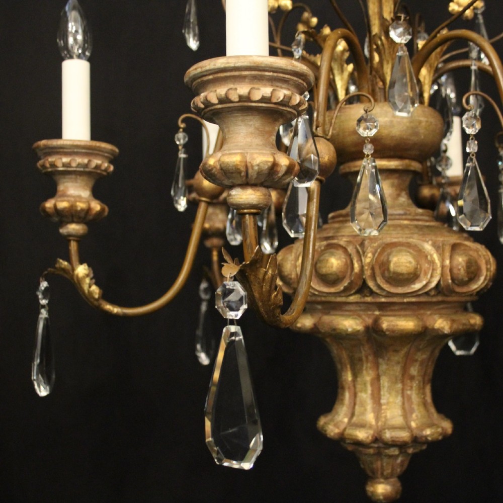 An antique Italian Florentine six-arm chandelier featuring gilded scrolling branches, a carved central column, white candle sleeves, and hanging crystal droplets. View V