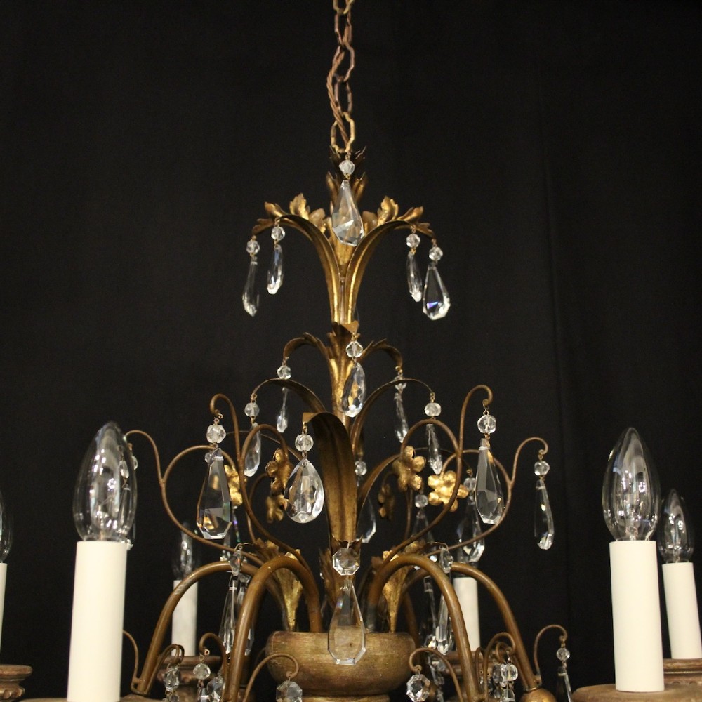 An antique Italian Florentine six-arm chandelier featuring gilded scrolling branches, a carved central column, white candle sleeves, and hanging crystal droplets. View VI