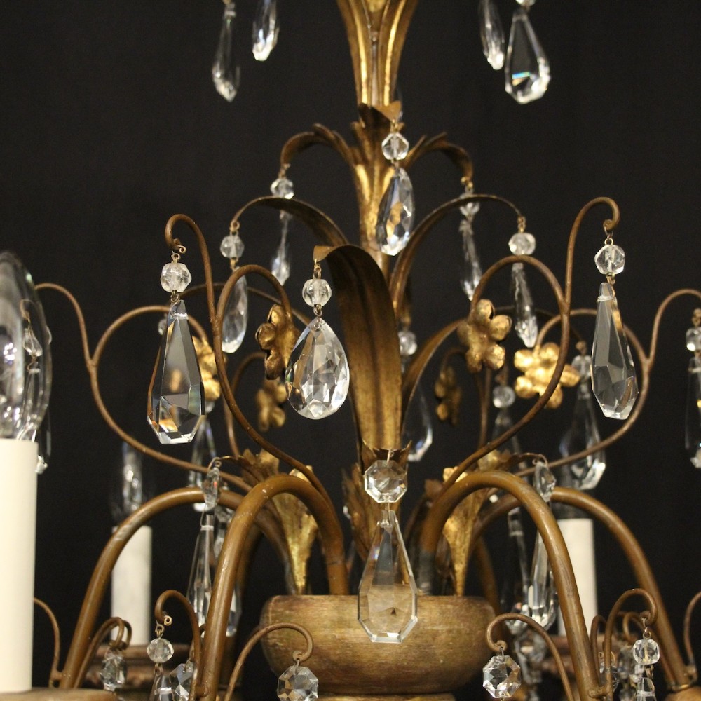 An antique Italian Florentine six-arm chandelier featuring gilded scrolling branches, a carved central column, white candle sleeves, and hanging crystal droplets. View VIII