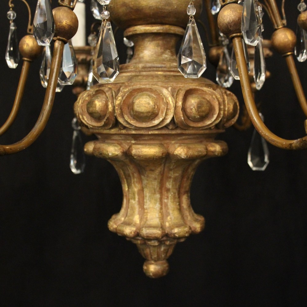 An antique Italian Florentine six-arm chandelier featuring gilded scrolling branches, a carved central column, white candle sleeves, and hanging crystal droplets. View IX