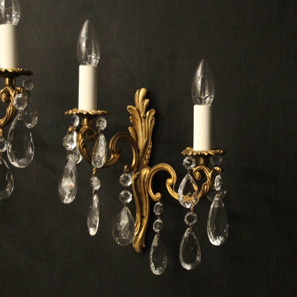 A pair of antique French gilt metal twin-arm wall sconces decorated with cut crystal teardrop pendants. View II