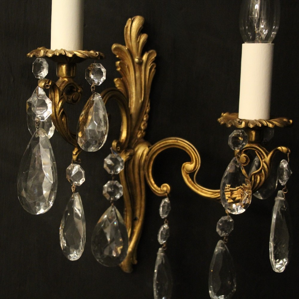 A pair of antique French gilt metal twin-arm wall sconces decorated with cut crystal teardrop pendants. View III