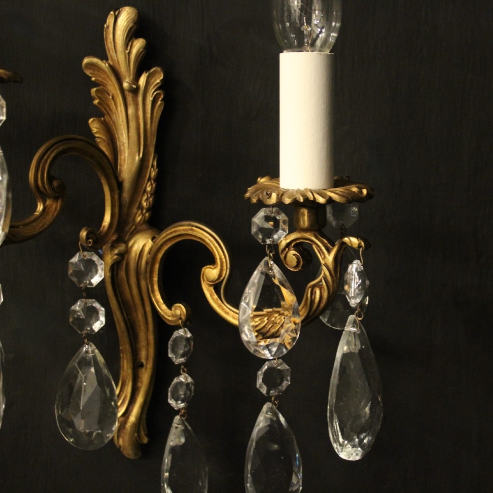 A pair of antique French gilt metal twin-arm wall sconces decorated with cut crystal teardrop pendants. View V