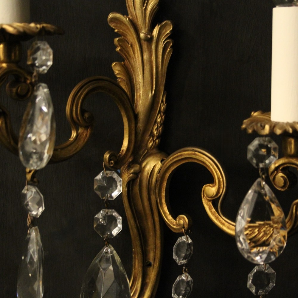 A pair of antique French gilt metal twin-arm wall sconces decorated with cut crystal teardrop pendants. View VIII