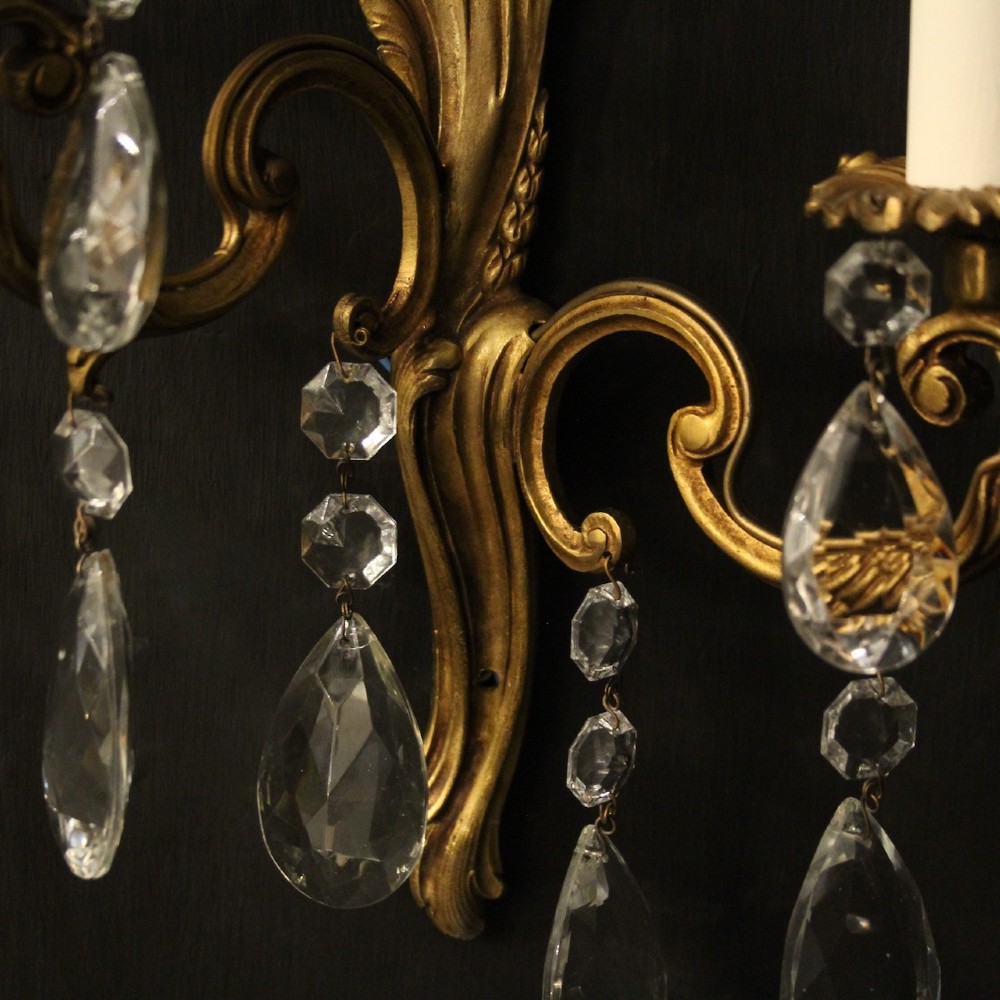 A pair of antique French gilt metal twin-arm wall sconces decorated with cut crystal teardrop pendants. View IX