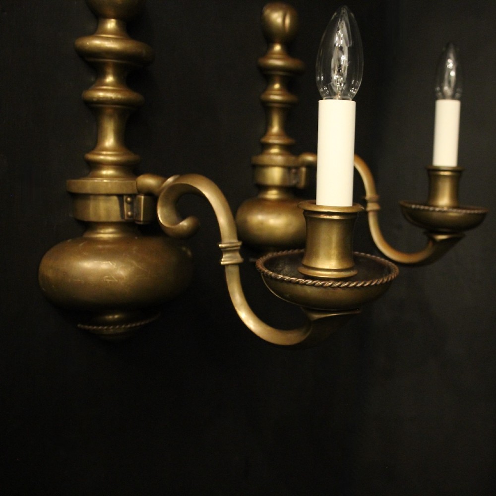 A pair of antique bronze single-arm wall lights with turned baluster shafts and candle-style fittings against a dark background. View III