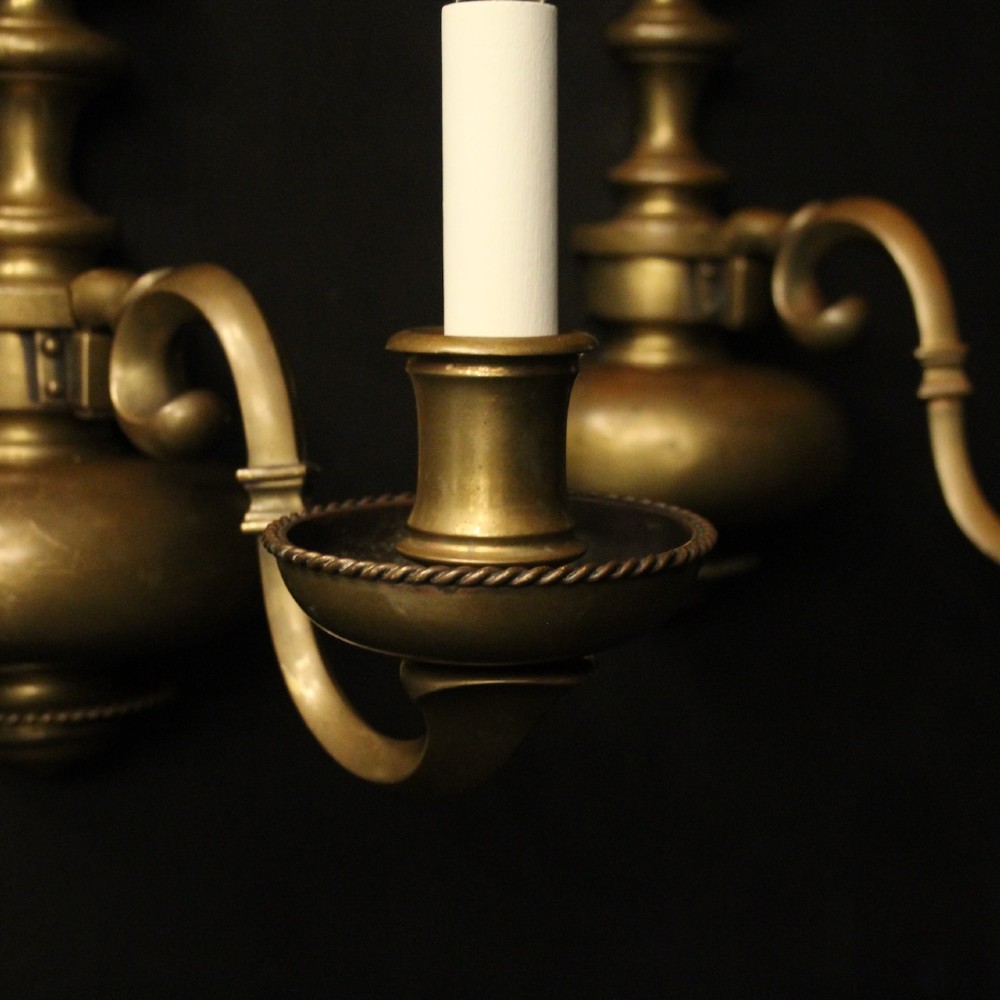 A pair of antique bronze single-arm wall lights with turned baluster shafts and candle-style fittings against a dark background. View IV