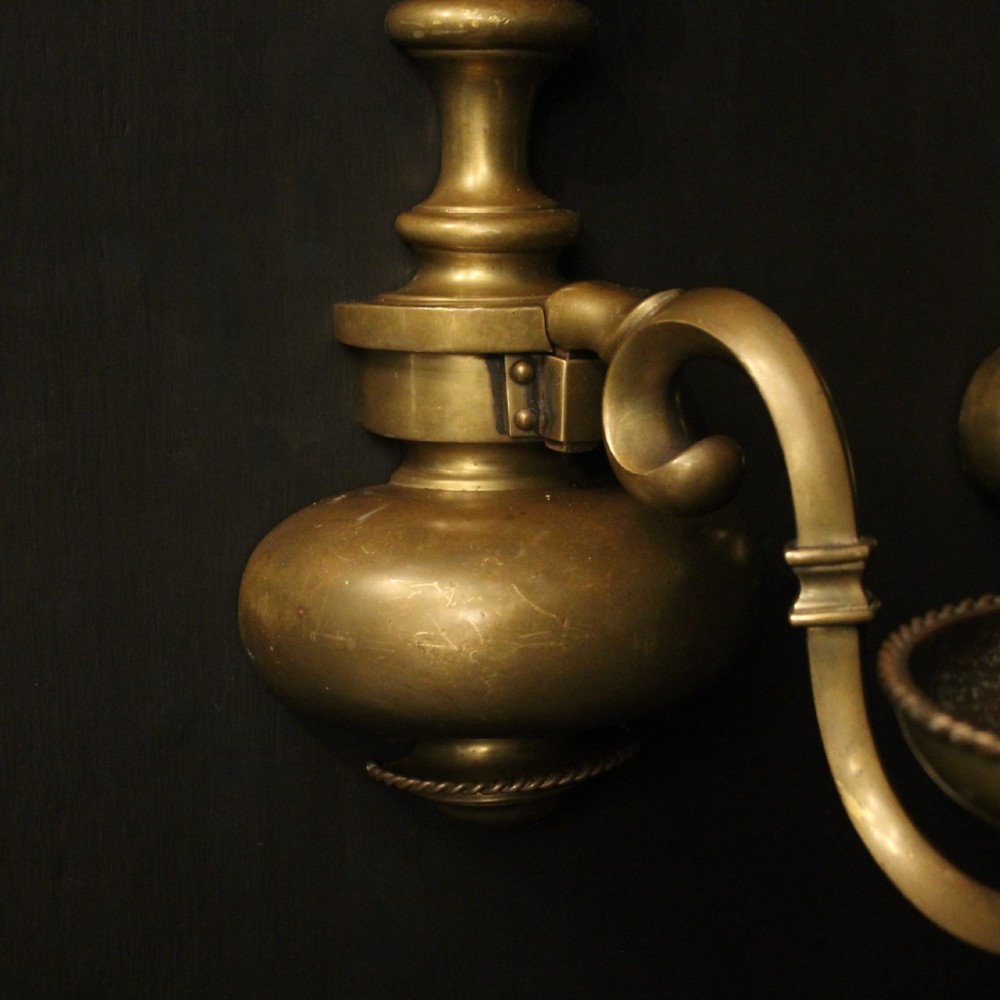 A pair of antique bronze single-arm wall lights with turned baluster shafts and candle-style fittings against a dark background. View V