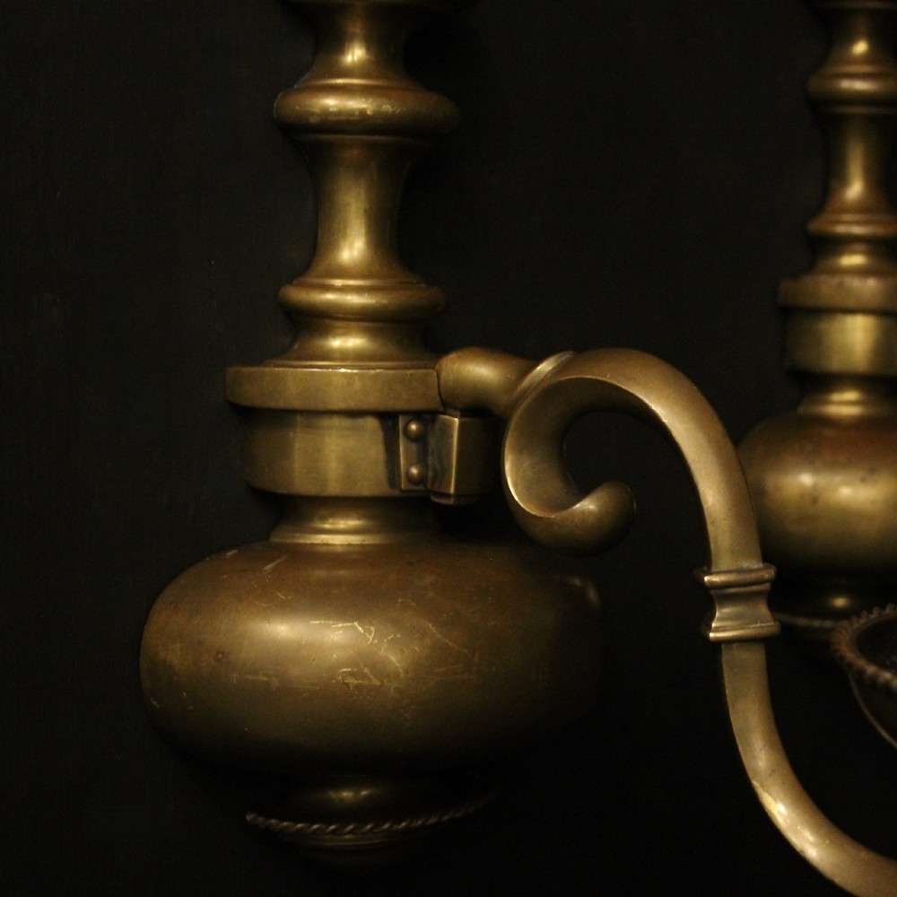 A pair of antique bronze single-arm wall lights with turned baluster shafts and candle-style fittings against a dark background. View VII