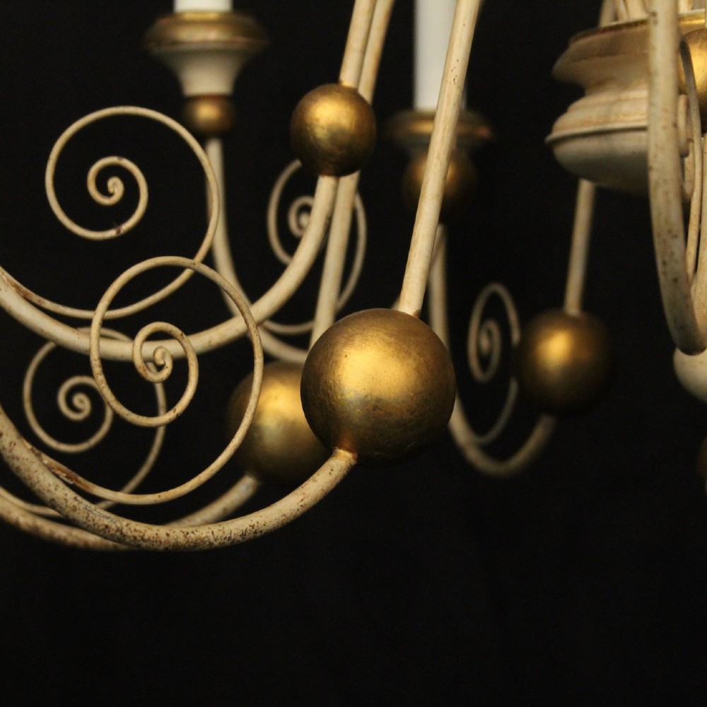 A twelve-light Florentine style ceiling chandelier featuring a cream and gilded turned wooden central column with wrought scrollwork branch arms and candle sleeves. View VII