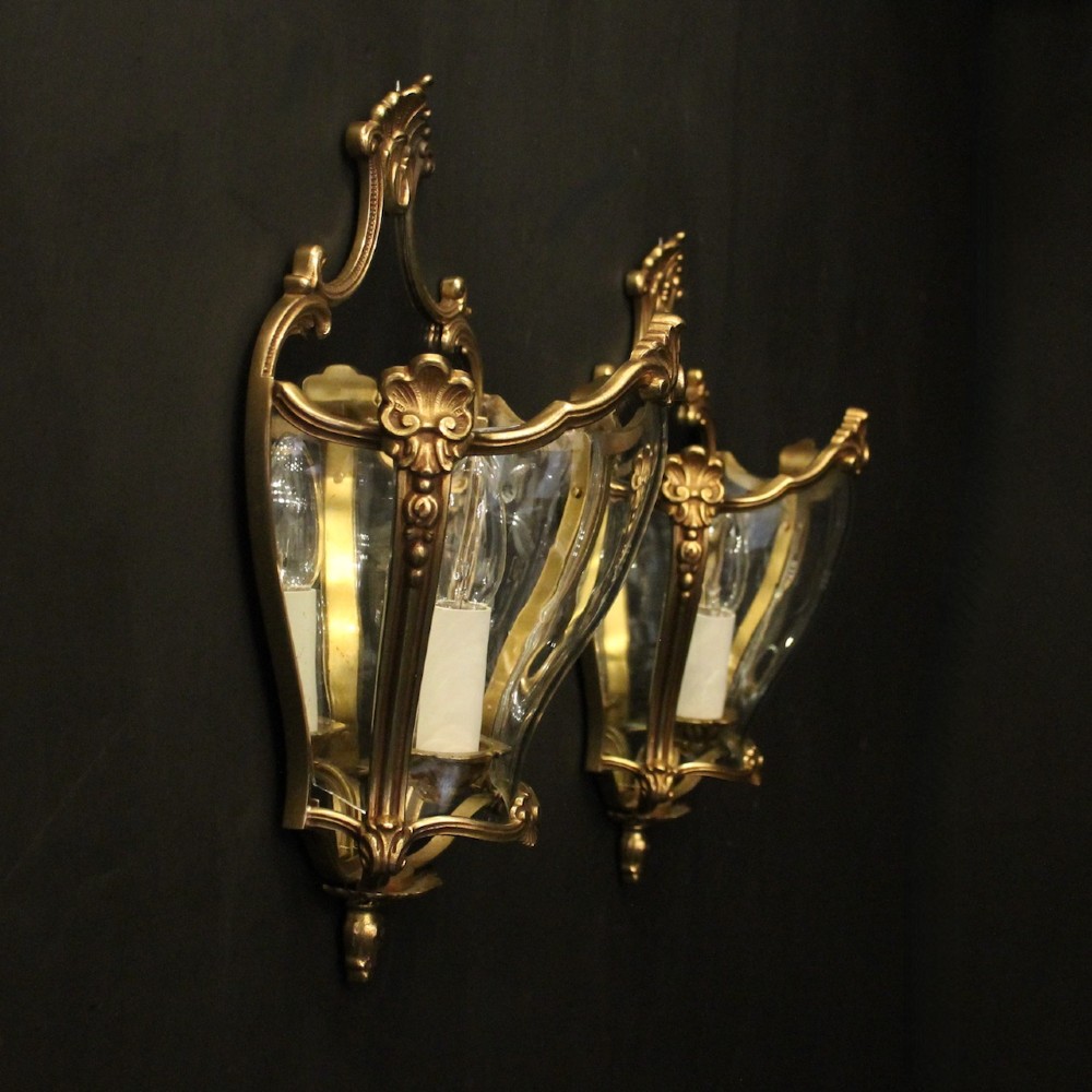 A pair of French gilded bronze half lanterns featuring curved glass panels and decorative palmette cresting, mounted as wall sconces. View X