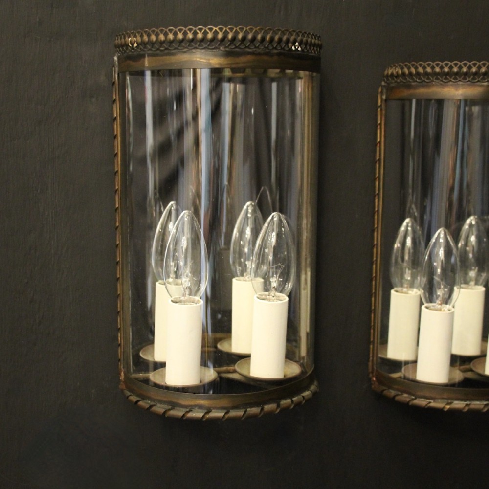 A pair of semi-circular brass half-lantern wall sconces featuring curved clear glass panels and four faux candle-bulb fittings inside each unit. View II