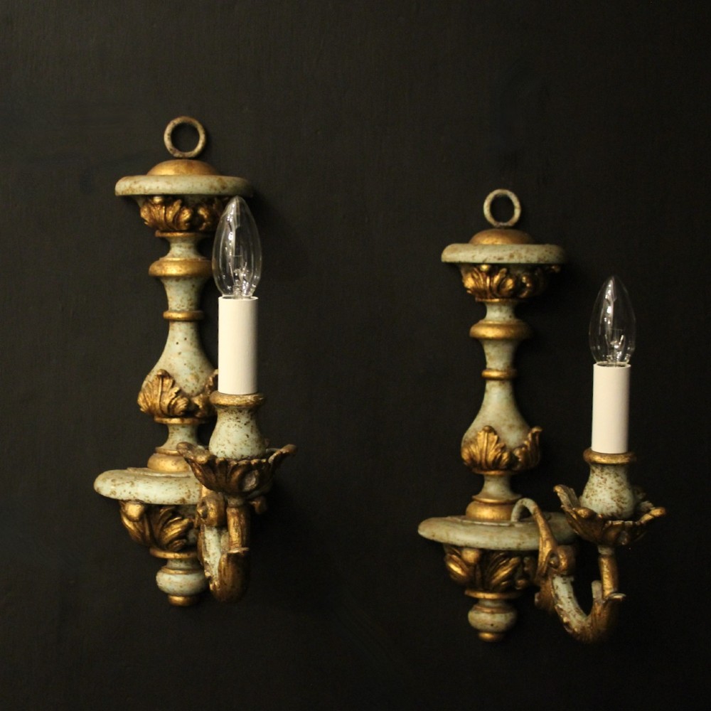 A pair of antique Italian wall lights featuring turned polychrome stems in pale green and gold with carved leaf accents and single candlestick arms. View II