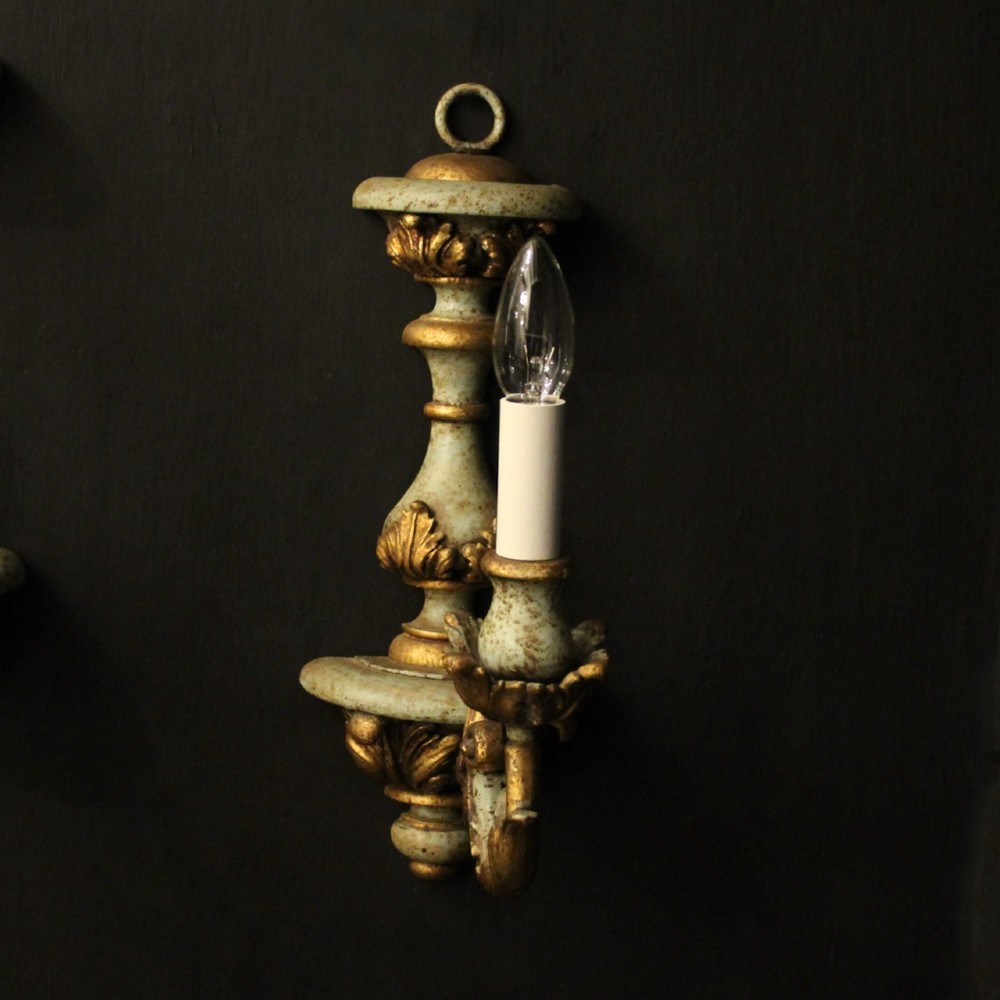 A pair of antique Italian wall lights featuring turned polychrome stems in pale green and gold with carved leaf accents and single candlestick arms. View III